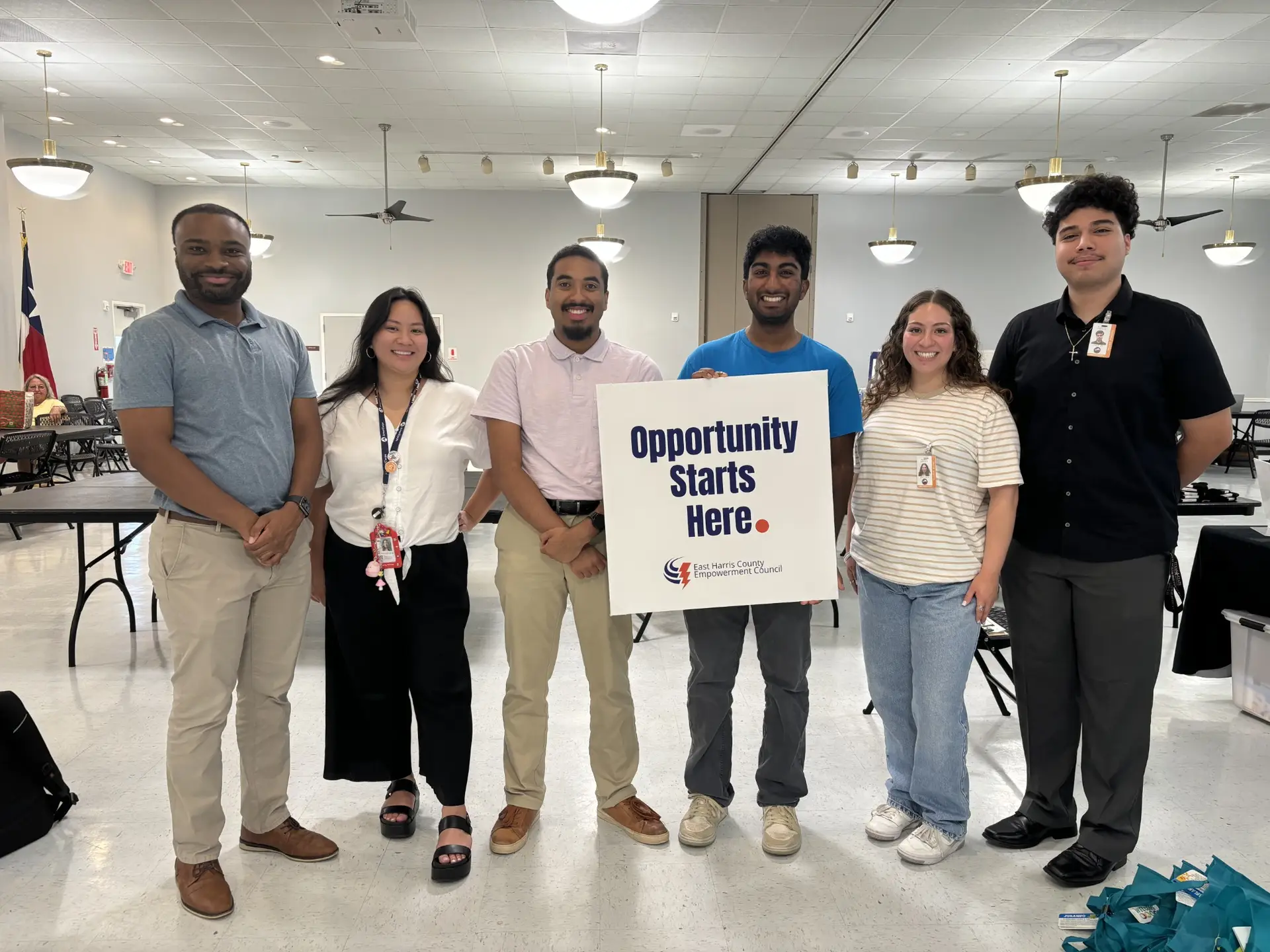 A group coming together at EHCEC with an Opportunity Starts Here sign.